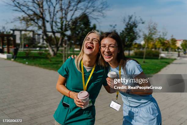 two young female nurses cheerfully embracing - lunch break stockfoto's en -beelden