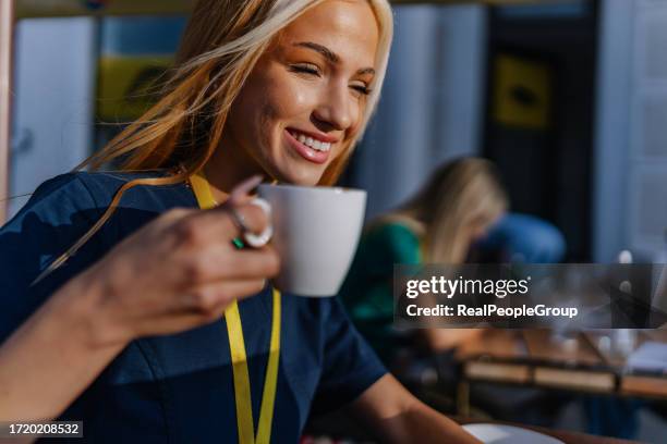 close-up of a young female nurse smiling and enjoying her coffee in the sun - nurse silence stock pictures, royalty-free photos & images