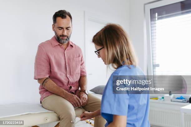 doctor testing patient’s reflexes, using reflex hammer. - neuropathy stockfoto's en -beelden