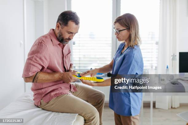 diabetologist showing patient diabetic shoe inserts. - diabetes feet stock pictures, royalty-free photos & images