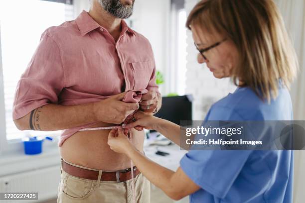 diabetologist doctor measuring patient’s waist, examine abdominal obesity in diabetes clinic. - glucose stock pictures, royalty-free photos & images