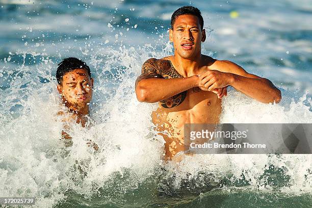 Israel Folau and Christian Leali'ifano are hit by a wave during an Australian Wallabies recovery session at Coogee Beach on July 1, 2013 in Sydney,...