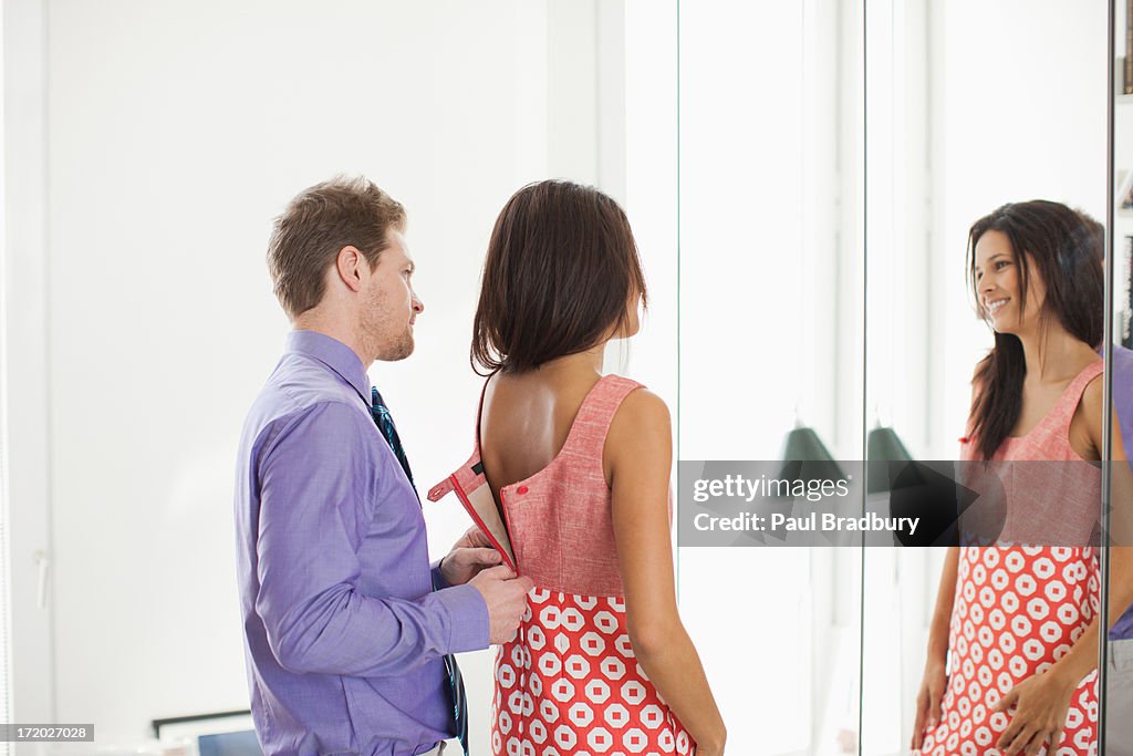 Man zipping wifes dress for her