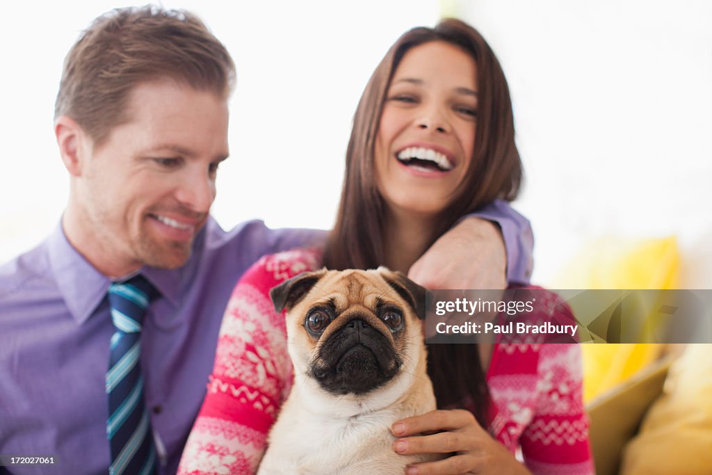 Smiling couple holding cute, small dog