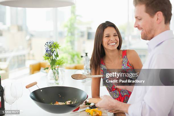 woman watching husband flipping stirfry in the kitchen - stir frying european stock pictures, royalty-free photos & images