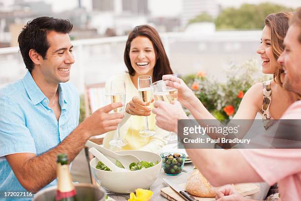 ridendo coppia brindando con champagne all'aperto - four people foto e immagini stock