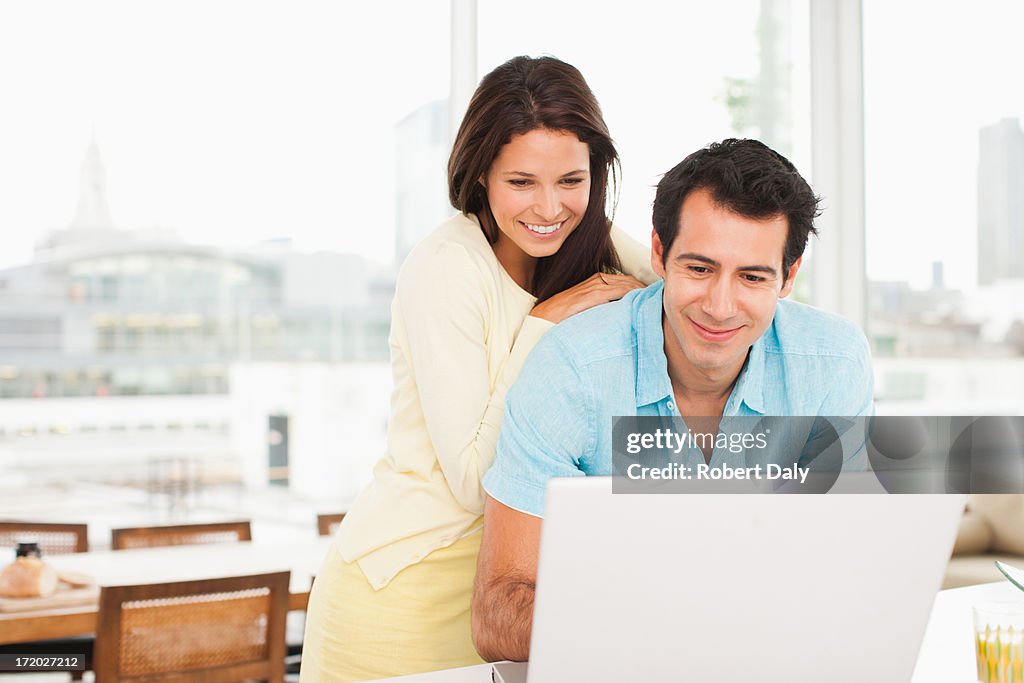 Smiling couple using laptop