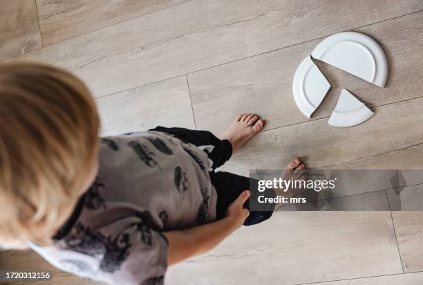 little boy  standing next to broken plate - assiette cassée photos et images de collection