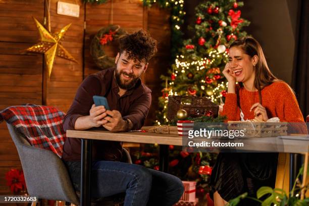 cheerful young man showing a meme to his girlfriend via smart phone - girlfriend meme stock pictures, royalty-free photos & images