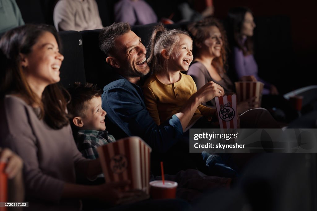 Cheerful family watching a funny movie in theatre.