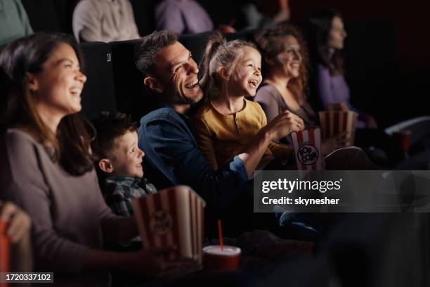 cheerful family watching a funny movie in theatre. - girls boys opening night stock pictures, royalty-free photos & images