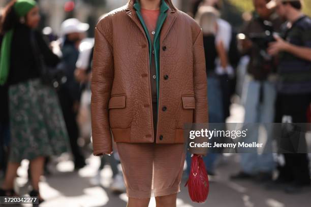 Ginevra Mavilla is seen wearing an oversized cognac jacket with a green collar, including a coral top and a beige long cardigan, thin brown...