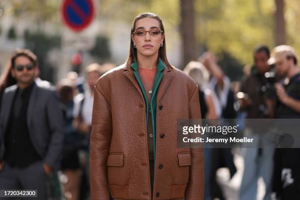 Ginevra Mavilla is seen wearing an oversized cognac jacket with a green collar, including a coral top and a beige long cardigan, thin brown...