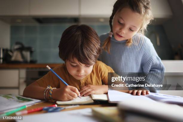 an 8-year-old girl helping her little brother with his homework - sister stock pictures, royalty-free photos & images