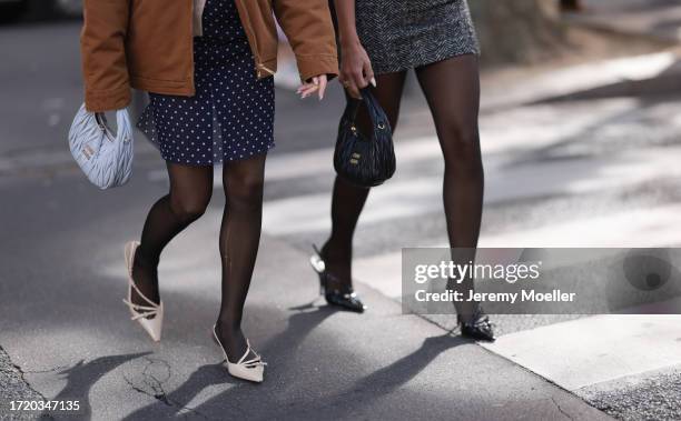 Emili Sindlev is seen wearing a beige cardigan, with a brown jacket from Carhartt, dark blue shorts with white dots, a gray Miu Miu Hobo handbag,...