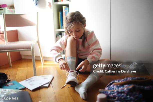 an 8 year old girl preparing to go to school, she's tying her shoeslaces - schnürsenkel stock-fotos und bilder