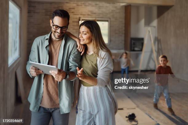 padres felices usando una tableta digital en su nuevo hogar. - renovación del hogar fotografías e imágenes de stock