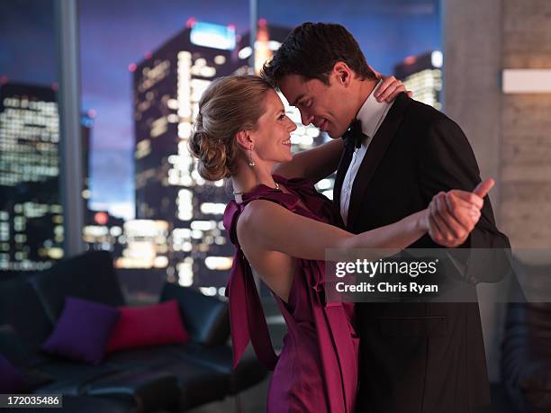 elegant couple dancing in living room - goed gekleed stockfoto's en -beelden
