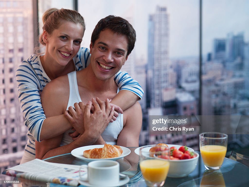 Couple hugging with breakfast on the table