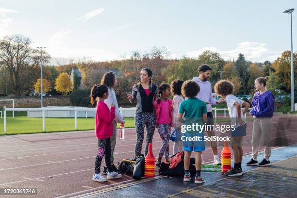 coach im gespräch mit der laufgruppe - sportfest stock-fotos und bilder
