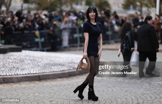 Momo is seen wearing a black short dress, black tights, high black boots and a Miu Miu bag with brown teddy fur during the Miu Miu Show Womenswear...