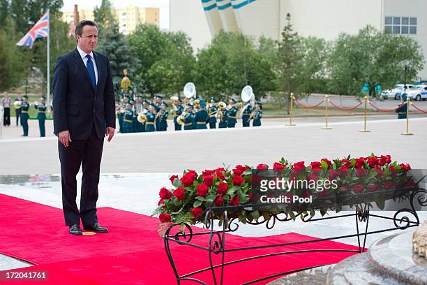 British Prime Minister David Cameron pays his respects after laying a wreath at the Monument of the Motherland Defenders on July 1, 2013 in Astana,...