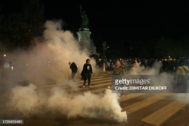 Protestors stand in clouds of tear gas as police try to disperse an unauthorized demonstration in support of Palestinians at Place de la Republique,...