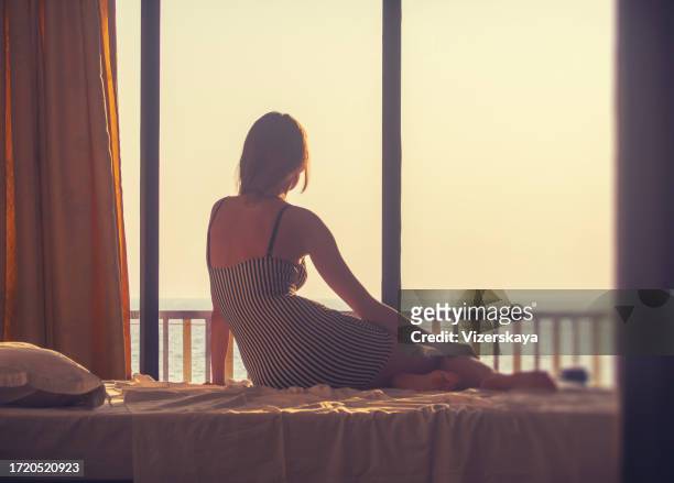 young woman in sunset room - woman back pillow blonde stock pictures, royalty-free photos & images