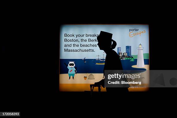 The silhouette of a flight attendant is seen walking past a Porter Airlines Inc. Advertisement at Billy Bishop Toronto City Airport in Toronto,...