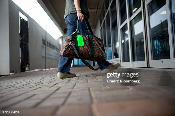 Traveler carries luggage while entering Billy Bishop Toronto City Airport in Toronto, Ontario, Canada, on Friday, June 28, 2013. Porter Airlines...