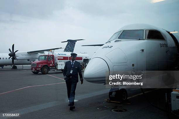 Porter Airlines Inc. Pilot walks past an aircraft at Billy Bishop Toronto City Airport in Toronto, Ontario, Canada, on Friday, June 28, 2013. Porter...