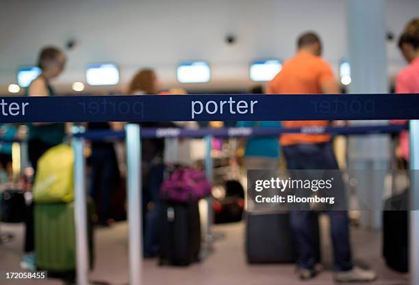 Travelers stand in line at a Porter Airlines Inc. Check-in counter at Billy Bishop Toronto City Airport in Toronto, Ontario, Canada, on Friday, June...