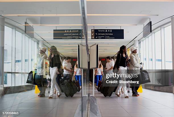 Travelers walk through a hallway at Billy Bishop Toronto City Airport in Toronto, Ontario, Canada, on Friday, June 28, 2013. Porter Airlines Inc.,...