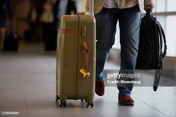 Traveler carries luggage at Billy Bishop Toronto City Airport in Toronto, Ontario, Canada, on Friday, June 28, 2013. Porter Airlines Inc., the...