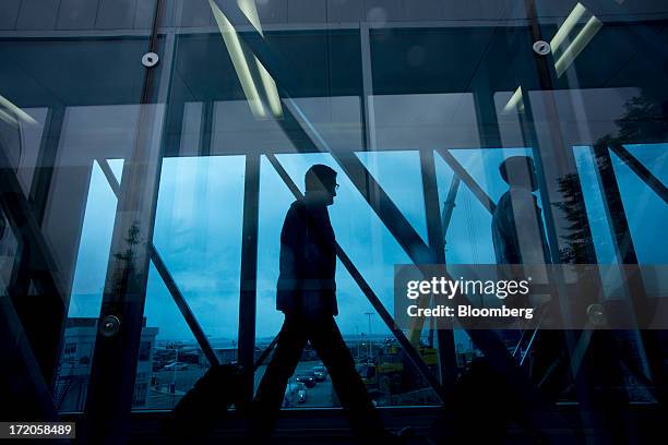 Travelers walk through a walkway at Billy Bishop Toronto City Airport in Toronto, Ontario, Canada, on Friday, June 28, 2013. Porter Airlines Inc.,...