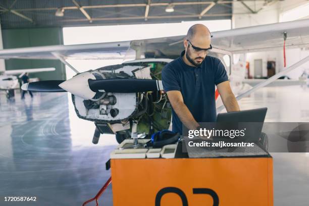 un mecánico de aviones está dando servicio al avión en el taller - airplane part fotografías e imágenes de stock
