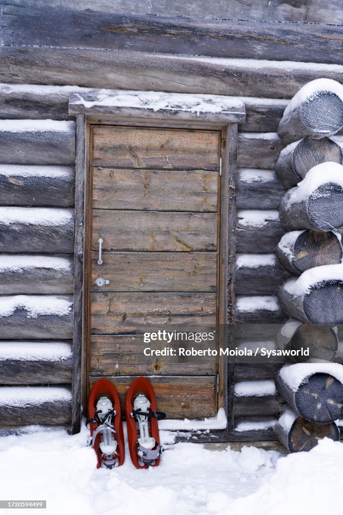 Snowshoes out a wood chalet covered with snow
