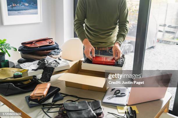 an unrecognisable man packages up a second hand purse that he's just sold online - box purse stock-fotos und bilder