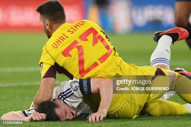 Spain's goalkeeper Unai Simon falls on Scotland's defender Andrew Robertson during the EURO 2024 first round group A qualifying football match...