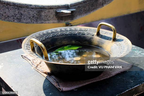 praying coins inside of bronze water sink - buddha's birthday stock-fotos und bilder