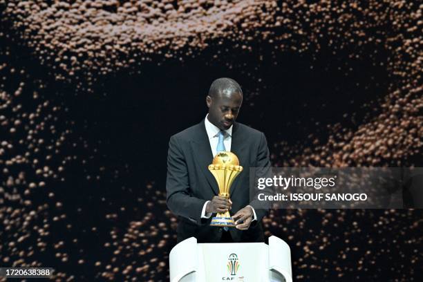 Former Ivorian footballer Yaya Toure brings the trophy on stage during the Africa Cup of Nations 2024 official draw at Parc des Expositions in...