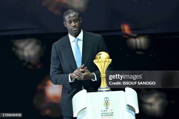 Former Ivorian footballer Yaya Toure puts the trophy on stage during the Africa Cup of Nations 2024 official draw at Parc des Expositions in Abidjan,...