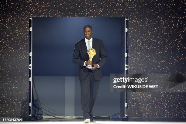 Former Ivorian footballer Yaya Toure brings the trophy on stage during the Africa Cup of Nations 2024 official draw at Parc des Expositions in...