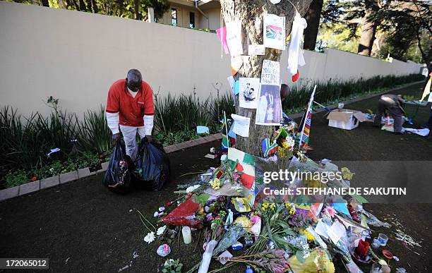 House keepers remove flowers and well wishing messages left for former South African President Nelson Mandela outside his house on July 1, 2013 in...