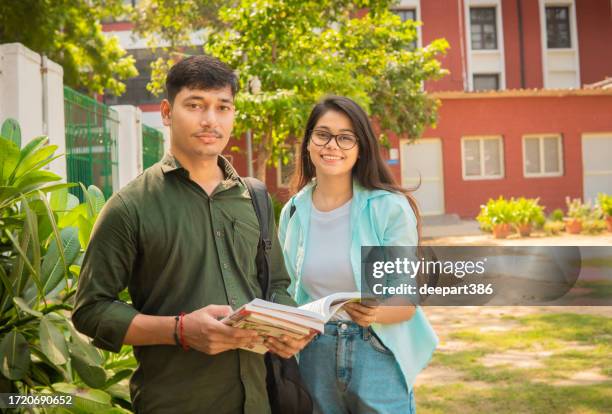 retrato de estudantes universitários sorridentes segurando um livro e olhando para a câmera. - indian college girl - fotografias e filmes do acervo