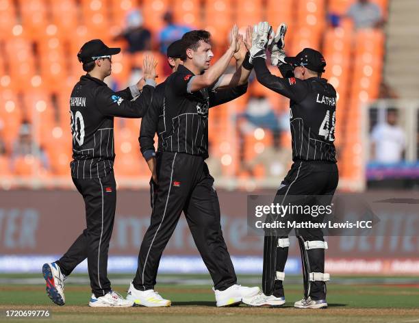 Tom Latham of New Zealand congratulates Matt Henry on the wicket of Jos Buttler of England during the ICC Men's Cricket World Cup India 2023 between...