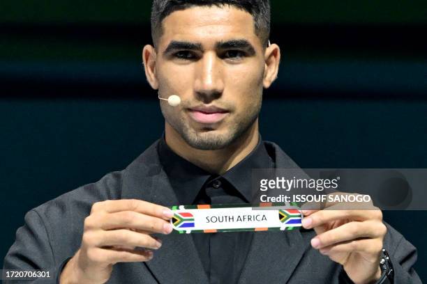 Morocco's footballer Achraf Hakimi shows the paper slip of South Africa during the Africa Cup of Nations 2024 official draw at Parc des Expositions...