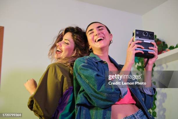 medium portrait of a young beautiful and confident women using a vintage camera on a house party - freedom to the camera stock pictures, royalty-free photos & images