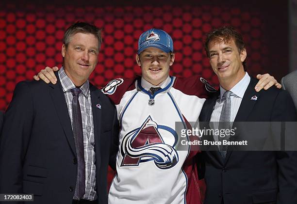 Nathan MacKinnon puts on his Colorado Avalanche jersey as he stands with head coach Patrick Roy and Joe Sakic after MacKinnon was selected number one...