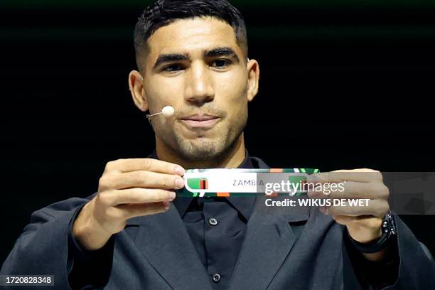 Morocco's footballer Achraf Hakimi shows the paper slip of Zambia during the Africa Cup of Nations 2024 official draw at Parc des Expositions in...